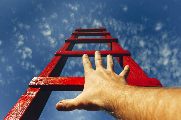istock Development Motivation Career Growth Concept. Mans Hand Reaching For Red Ladder Leading To A Blue Sky 922623658
