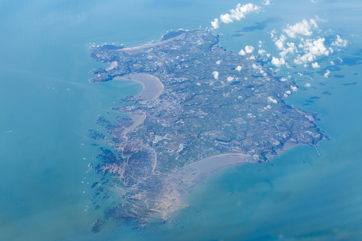 A photograph of the whole  island of Jersey, taken from the flight deck of an airplane