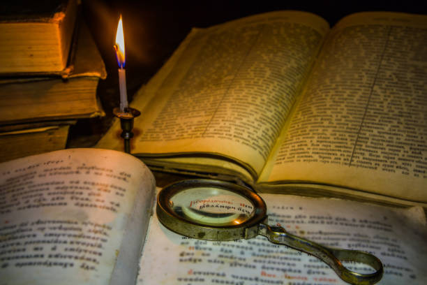 vieux livre et loupe verre sous la bougie lumineuse - magnification bible magnifying glass book photos et images de collection