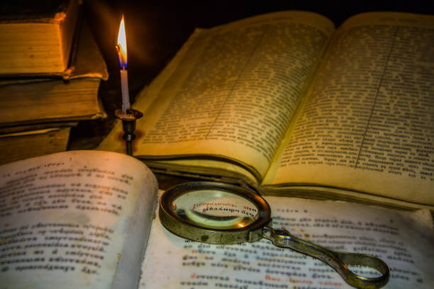 старая книга и увеличительное стекло под свечой - magnification bible magnifying glass book стоковые фото и изображения