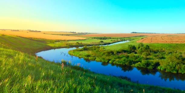 istock Sunny summer landscape.Green hills,fields and meadows.Sunrise.Quiet morning.Calm.Warm sunlight.Cloudless clear blue sky. 922645708