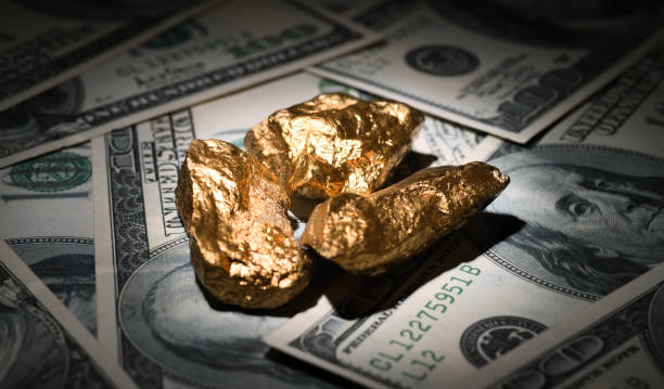 Gold nuggets and dollars Close up shot of gold nuggets on one hundred dollar bills. goldco reviews worth stock pictures, royalty-free photos & images