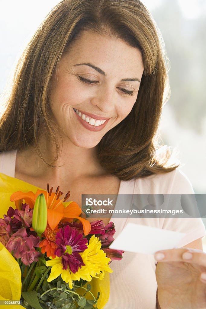 Woman holding flowers and reading note  Anniversary Stock Photo
