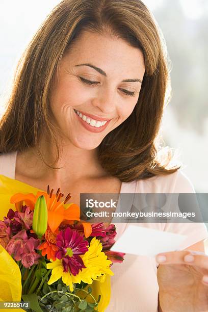 Woman Holding Flowers And Reading Note Stock Photo - Download Image Now - Anniversary, Flower, One Woman Only