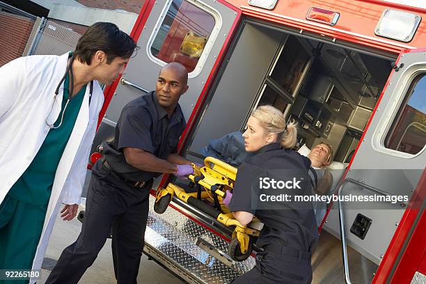 Paramedics Unloading Patient From Ambulance Stock Photo - Download Image Now - Ambulance, Paramedic, Doctor