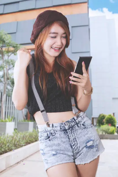Female teenager excited while looking at her phone
