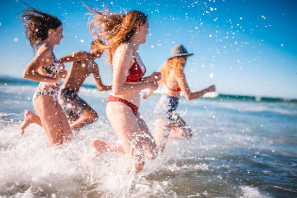 Group of friends in running on the beach on a sunny day in Australia. They are having fun.