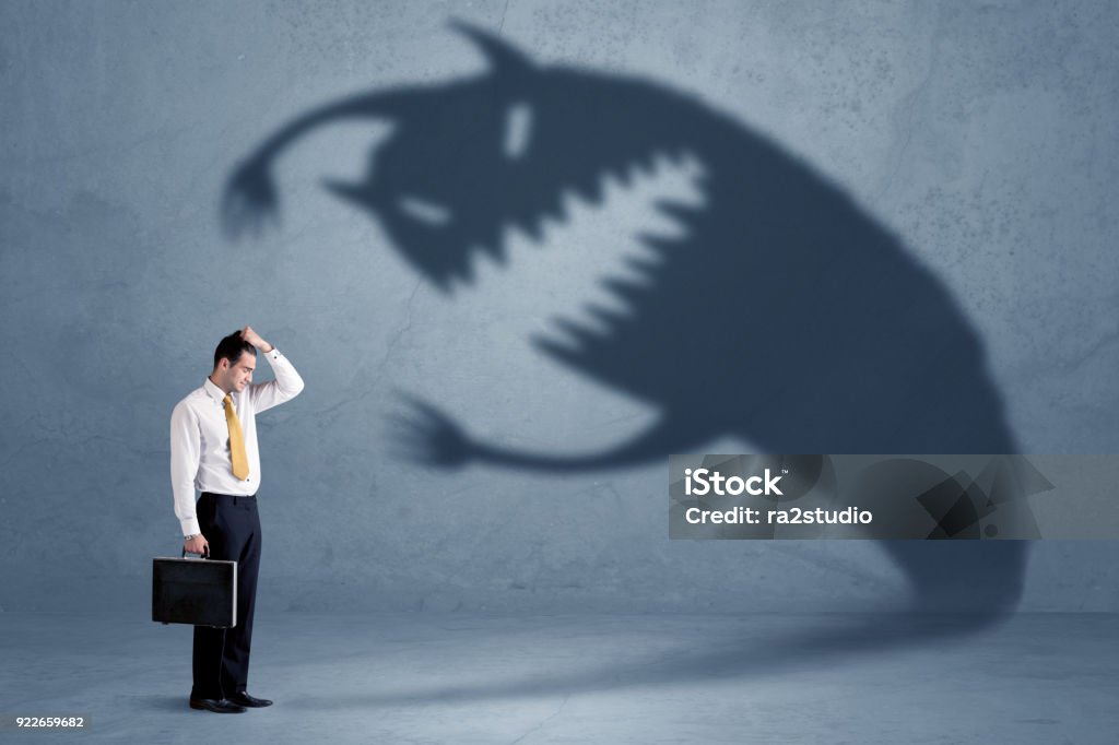 Business man afraid of his own shadow monster concept Business man afraid of his own shadow monster concept on grungy background Leadership Stock Photo