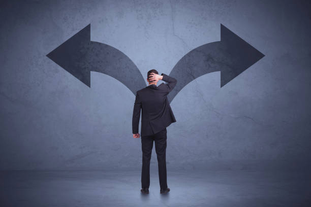 istock Businessman taking a decision while looking at arrows on the wall concept 922661732