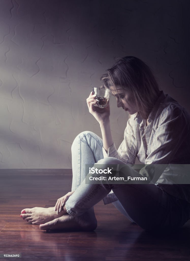 Depression Young woman in depression drinks alcohol while sitting on the floor Alcohol Abuse Stock Photo