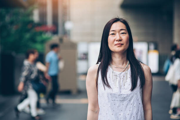 Japanese woman outdoors in the city Portrait of a middle aged Japanese woman standing outdoors with arms crossed serious stock pictures, royalty-free photos & images