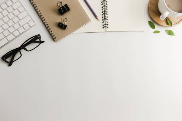 istock White office desk table with blank notebook, computer, supplies and coffee cup. Top view with copy space. Flat lay. 922663982