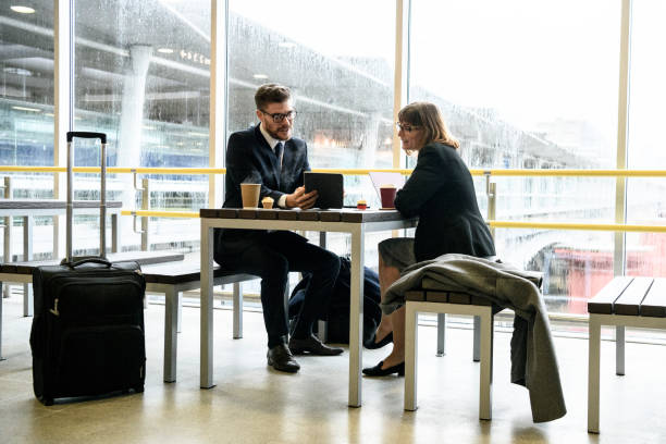 istock Business colleagues in railway station using tablet with wheeled suitcase 922664674