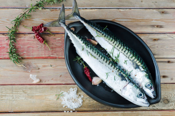 istock Two fresh mackerels in a black ceramic bowl with condiments. Upper plane. 922668390
