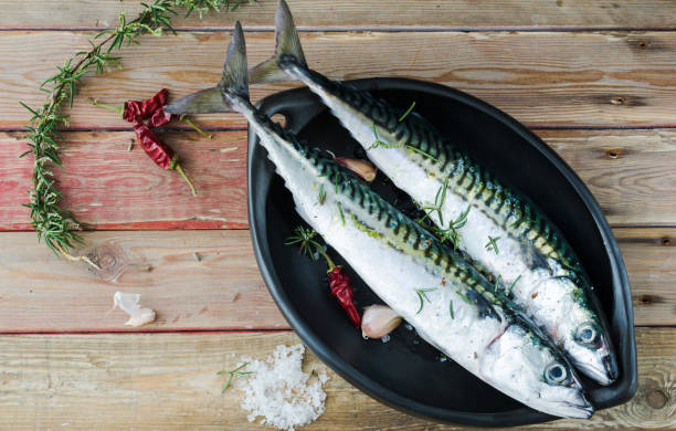 istock Two fresh mackerels in a black ceramic bowl with condiments. Upper plane. 922668400