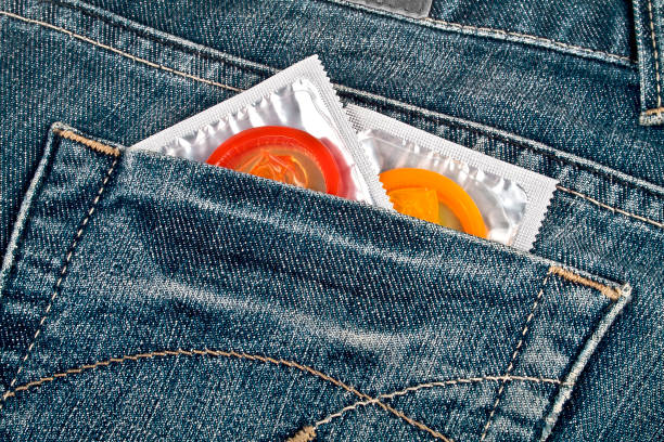 préservatifs colorés dans une poche de jeans bleu - sex condom jeans horizontal photos et images de collection