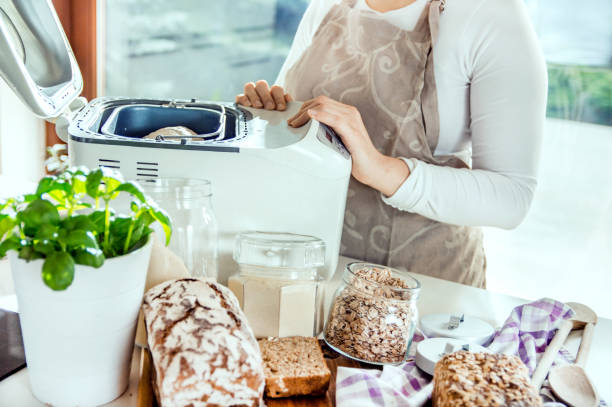 donna in una cucina moderna tra gli ingredienti per il pane fatto in casa prepara una macchina per la cottura - polish bread foto e immagini stock
