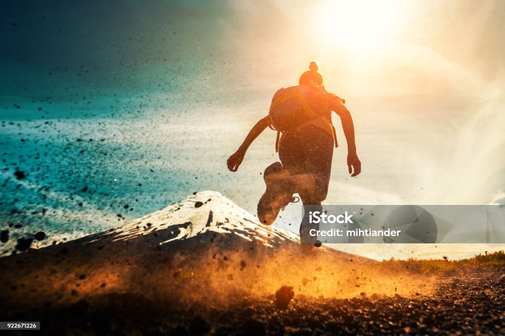 Woman athlete runs Woman athlete runs on a dirty and dusty ground with volcano on the background. Trail running athlete working out in the mountains Running Stock Photo