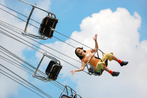 A girl feels as if she is flying, riding a chain swing ride at a carnival or amusement park.