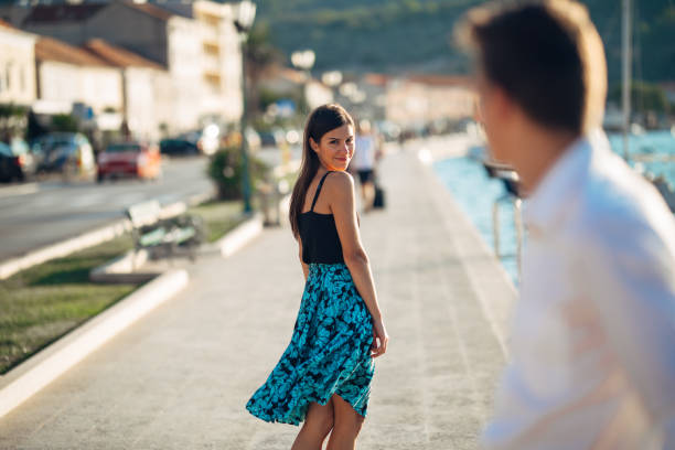 mujer atractiva joven coqueteando con un hombre de la calle. coqueta mujer sonriente mirando hacia atrás en un hombre guapo. atracción femenina. amor a primera vista. reunión de ex novio - turn back fotografías e imágenes de stock