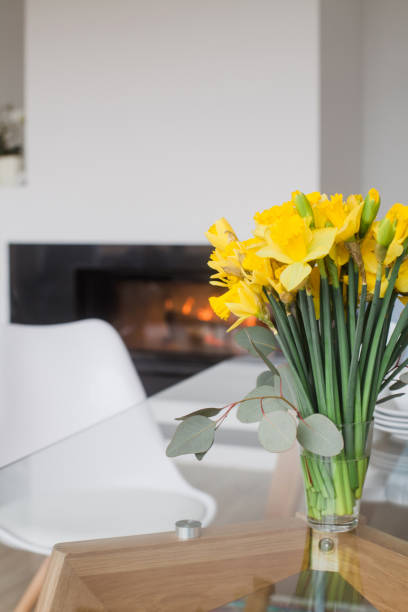 istock Glass table top with spring bouquet of daffodils with fireplace in background 922673986