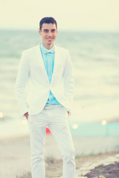 istock Young bridegroom in white clothes at sea cost 922677044