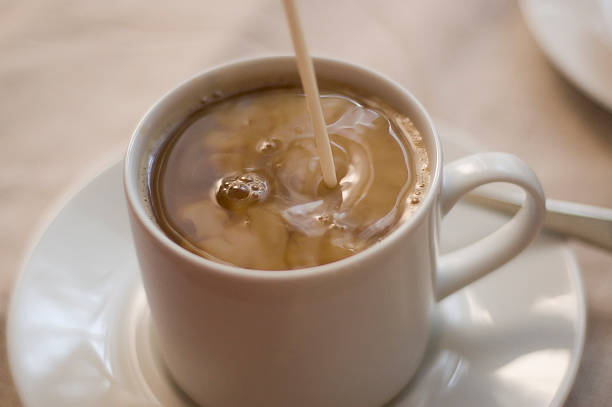 pouring cream into coffee stock photo