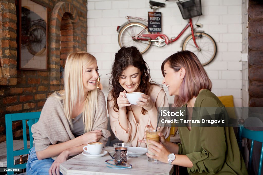 Coffee time with girlfriends Three women at cafe, talking,smiling,  laughing and enjoying their time. Lifestyle and friendship concepts with real people models. Women Stock Photo