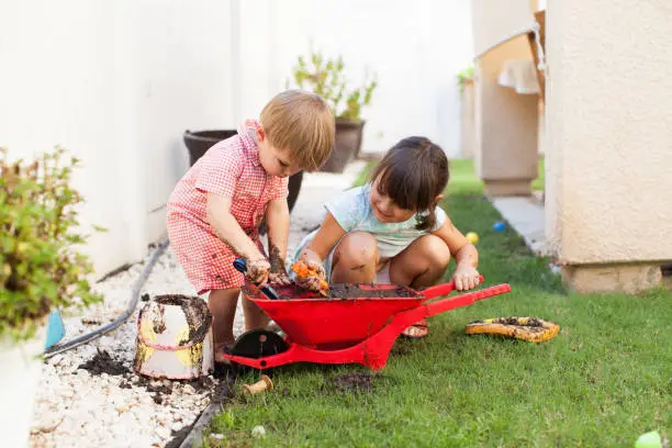 Photo of Toddler Kids Playing Outside With Mud in Summer