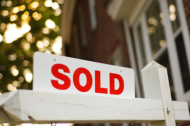 Sold sign Real Estate "sold" sign with red brick building and trees blurry in the background selling stock pictures, royalty-free photos & images