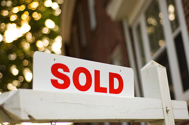 Sold sign Real Estate "sold" sign with red brick building and trees blurry in the background estate agent sign stock pictures, royalty-free photos & images