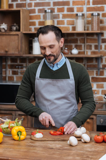 istock happy man cutting bell pepper in kitchen 922682830