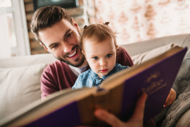 istock Father and daughter enjoying at home and reading a book 922685992