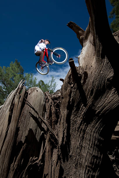 mountain biker pulando sobre um tronco - foto de acervo