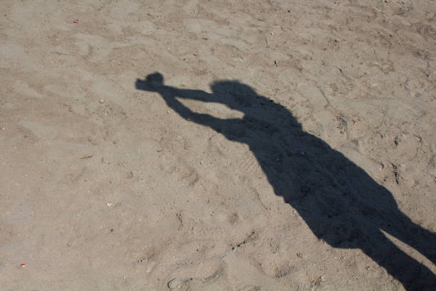 Shadow of a man on the sandy shore of a sea beach in the waves of water. Natural background.
