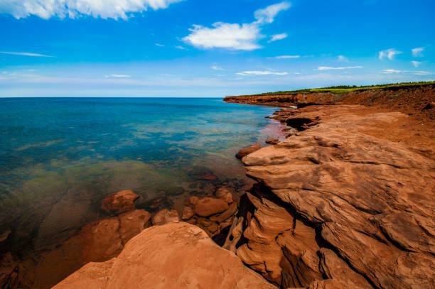 Rock cliff and clear water at Cavendish, Prince Edward Island Rock cliff and clear water at Cavendish, Prince Edward Island cavendish beach stock pictures, royalty-free photos & images