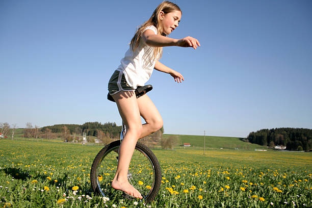 молодая девушка monocycling в поле - unicycle стоковые фото и изображения