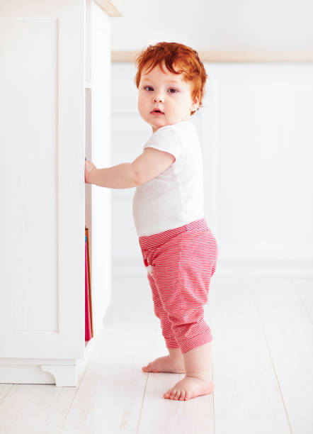 istock cute redhead baby boy standing in bright room 922699252