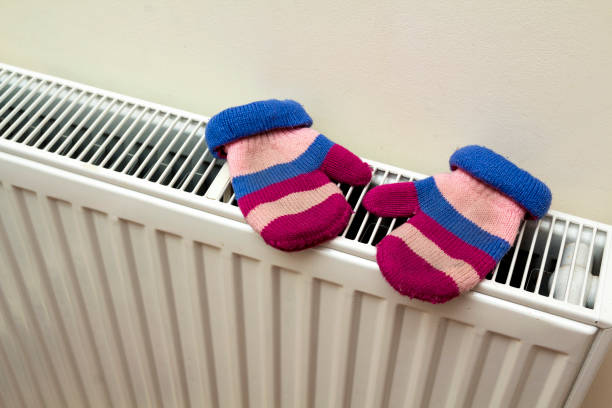 istock Children's warm hand knitted striped woolen gloves drying on hea 922700766