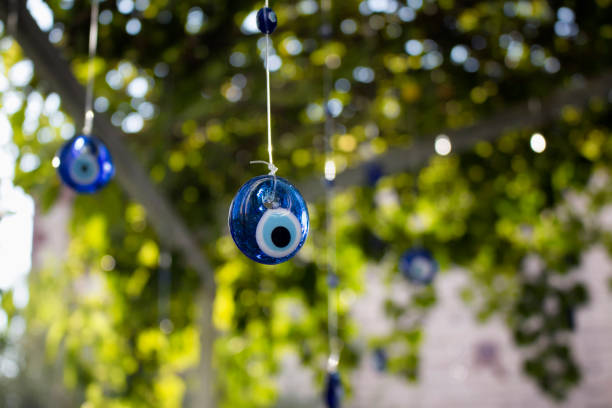 olhos diabólicos são pendurados em efeito decorativo com uma árvore no fundo na ilha cunda (tiago). - nazar boncugu - fotografias e filmes do acervo