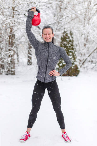 istock Happy young woman holding kettlebell in snow 922701544