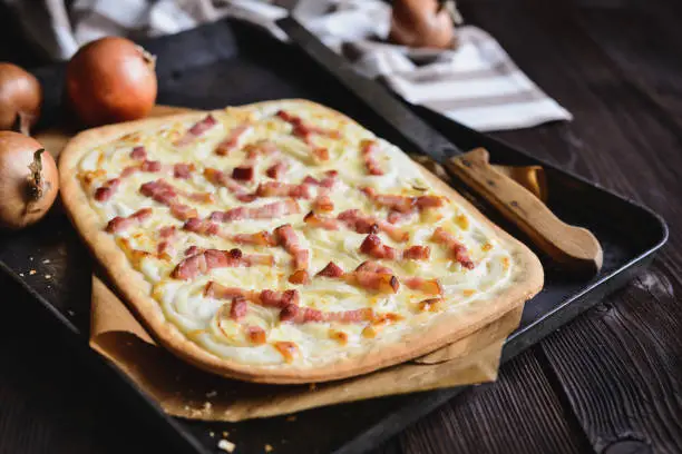Traditional Tarte flambée with crème fraiche, cheese, onion and bacon slices