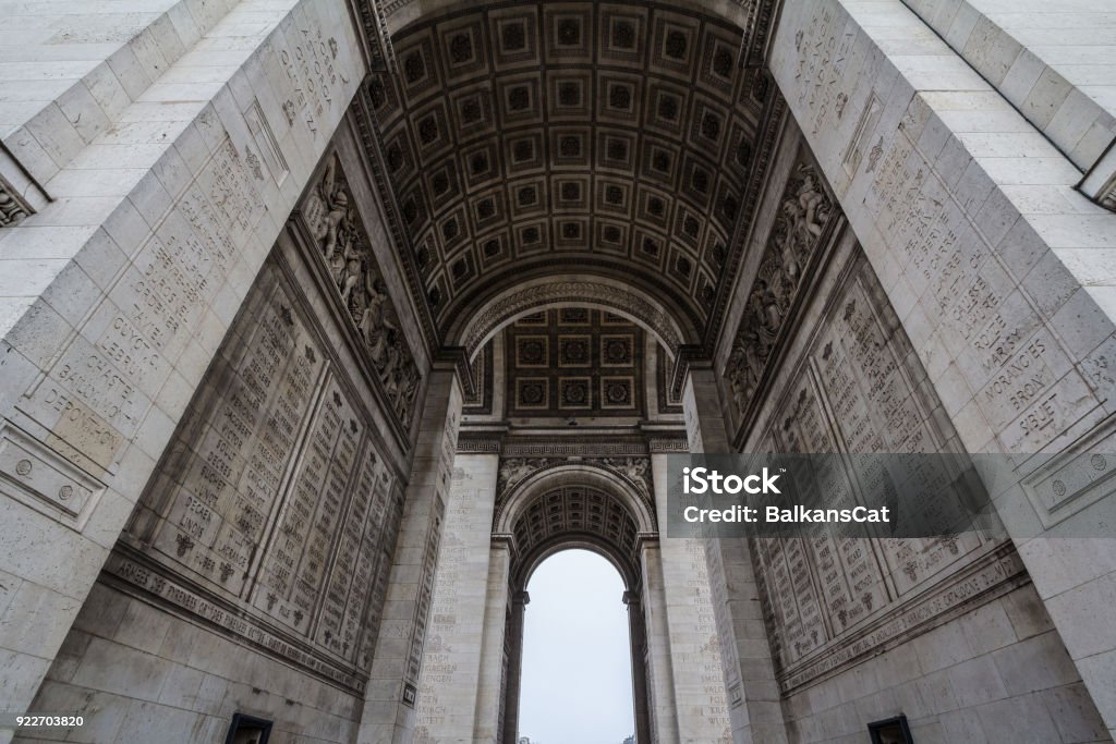 Arc de Triomphe (Triumph Arch, or Triumphal Arch) on place de l'Etoile in Paris, taken from below. It is one of the most famous monuments in Paris, standing at the end of Champs Elysees at the center of Place Charles de Gaulle Picture of Arc de Triomphe in Paris, France, taken from below during a clod rainy cloudy afternoon. This Arch is one of the main monuments and landmarks of the capital city of France, built in the 19th century to celebrate Napoleon legacy Arc de Triomphe - Paris Stock Photo