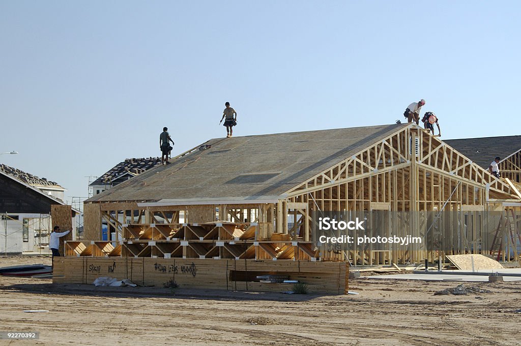 Construction workers standing on framework of new home New home being built in a residential area. Architecture Stock Photo