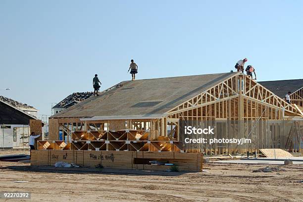Construction Workers Standing On Framework Of New Home Stock Photo - Download Image Now