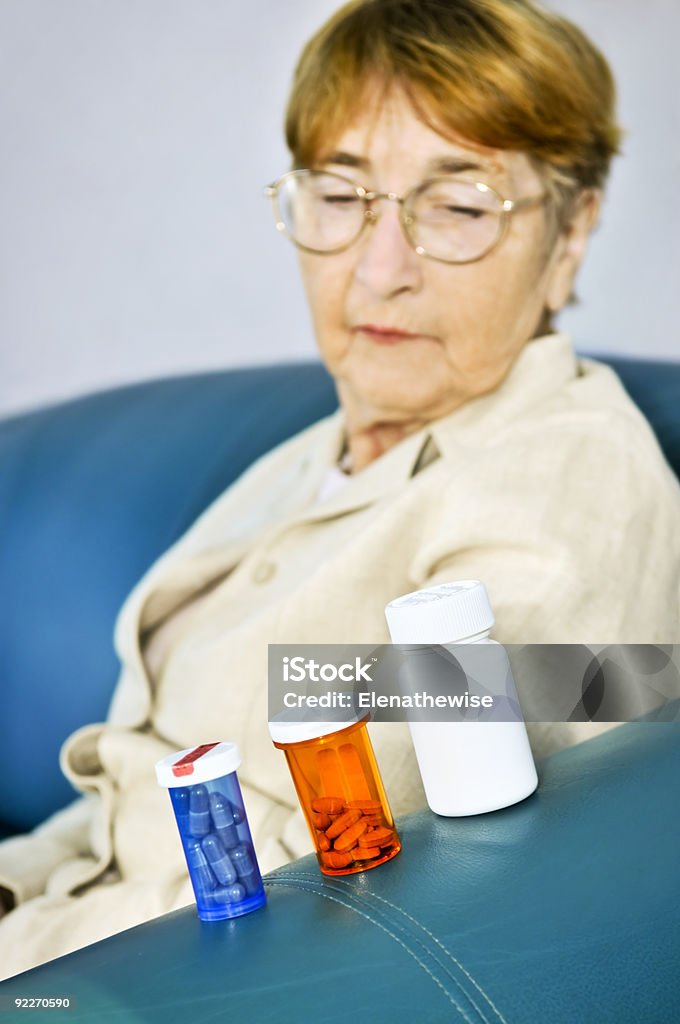 Starszy kobieta Patrząc na tabletki butelek - Zbiór zdjęć royalty-free (Butelka)