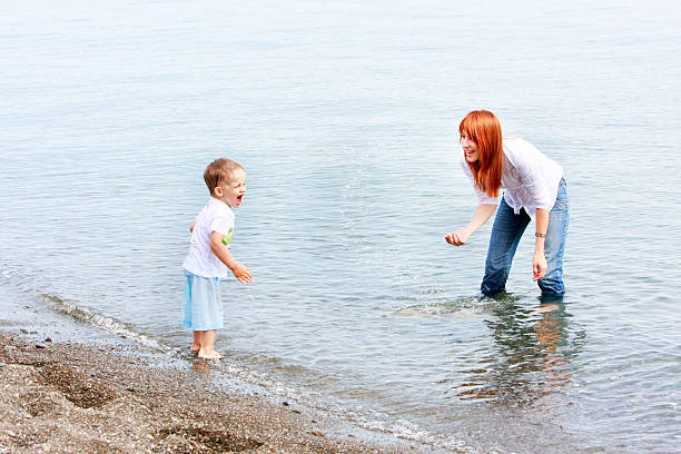 istock mother and son playing in water on beach 92271281