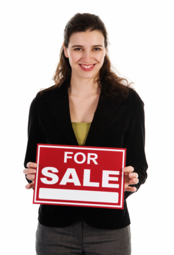 smiling business woman holding up a SOLD sign against white background