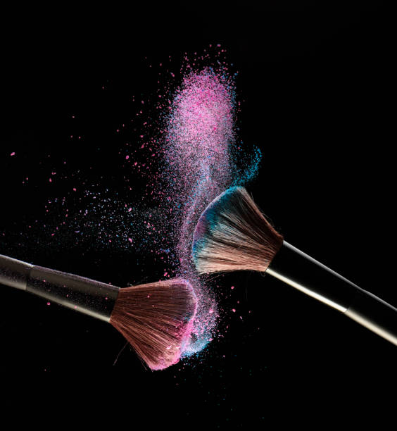pincéis de maquilhagem com explosão de pó-de-rosa e azul sobre fundo preto - face powder fotos - fotografias e filmes do acervo