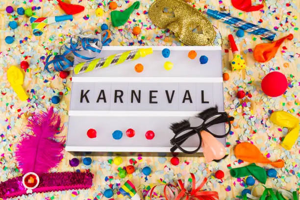 Lightbox with letters - KARNEVAL means HAPPY CARNEVAL - on colorful festive party decoration with steamers, confetti and ballons.